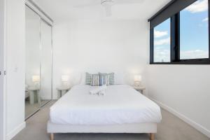 a white bedroom with a large bed and a window at Riverside Modern Living 2B2B Apt with Parking in Brisbane +23 photos