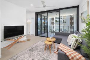 a living room with a couch and a tv at Riverside Modern Living 2B2B Apt with Parking in Brisbane