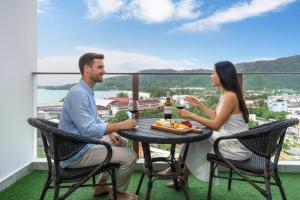 a man and a woman sitting at a table on a balcony at Studio Apt Seaview Balcony - Oceana C63 in Kamala Beach