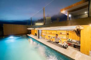 a man sitting at a bar next to a swimming pool at The All New Stark Boutique Hotel in Kuta