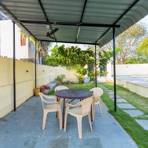patio con tavolo e sedie sotto un baldacchino di Le Haayt Resort With pool a Pondicherry Altre 21 foto