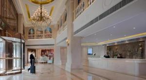 a man standing in a lobby with a suitcase at Vienna Hotel Guizhou Liupanshui Shuicheng Ancient Town in Shuicheng