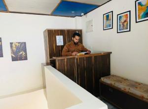 Ein Mann sitzt an einem Tresen in einem Museum. in der Unterkunft Boho Regency in Shimla