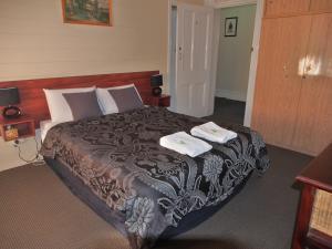 a bedroom with a bed with two towels on it at Great Central Hotel in Glen Innes