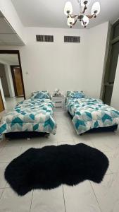 1 Schlafzimmer mit 2 Betten und einem schwarzen Teppich in der Unterkunft Bed space in master room in Schardscha