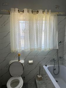 ein Bad mit einem WC, einer Badewanne und einem Fenster in der Unterkunft Hatfield staylax Manor 1 in Harare