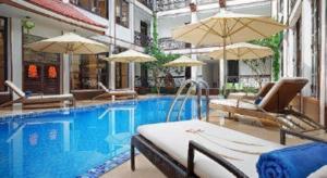 una piscina con sillas y sombrillas en Vinh Hung 2 City Hotel, en Hoi An