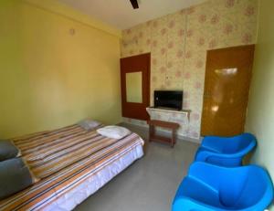 a bedroom with a bed and two blue chairs at Family Guest House Pondicherry in Vānūr