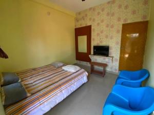 a bedroom with a bed and two blue chairs at Family Guest House Pondicherry in Vānūr +5 photos