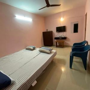 a bedroom with a bed and a blue chair at Family Guest House Pondicherry in Vānūr