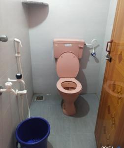 a bathroom with a pink toilet and a blue bucket at Family Guest House Pondicherry in Vānūr