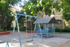 a playground with a swing in front of a building at Moonbay Marina the Villas in Olongapo