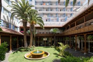 une cour avec une fontaine et des palmiers devant un bâtiment dans l'établissement Catalonia Las Vegas - Adults Only, à Puerto de la Cruz