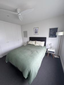 a bedroom with a large green bed with a ceiling fan at Inner city quiet cottage in Melbourne