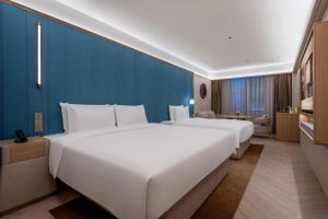 青岛桔子水晶青岛台东步行街延安三路酒店的酒店客房内设有两张大型白色床。 更多28张照片