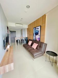 Apartemen Patraland Amarta Yogyakarta في Kejayan: غرفة معيشة مع أريكة بنية وطاولة