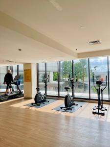 Apartemen Patraland Amarta Yogyakarta في Kejayan: صالة ألعاب رياضية مع أجهزة جري ودراجات ممارسة الرياضة في غرفة بها نوافذ +17 صورة