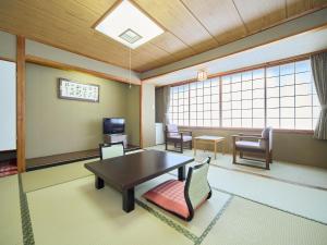 ein Wohnzimmer mit Tisch und Stühlen und Fenstern in der Unterkunft Hotel Kameya in Osaki