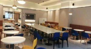 上海GreenTree Inn Shanghai National Convention and Exhibition Center Huaxiang Road的一间有桌椅和一张大桌子的自助餐厅