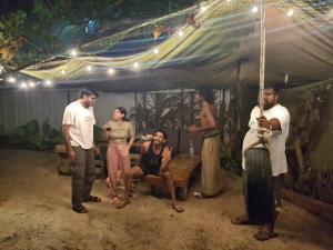 Un grupo de personas de pie bajo una tienda de campaña. en Sadhana on the beach, en Alleppey