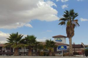 a hotel with palm trees in front of a building at Days Inn by Wyndham Victorville in Victorville