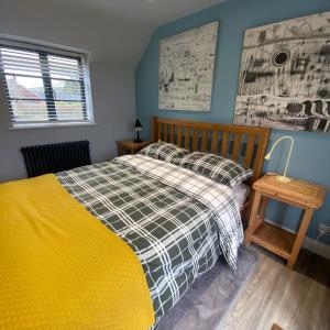 a bedroom with a bed with a plaid blanket and a window at Cold Kitchen View in Longbridge Deverill
