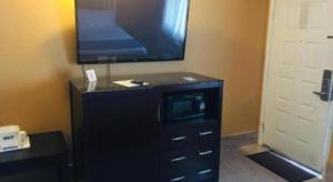 uma cómoda preta com uma televisão em cima em Travelodge by Wyndham Bay Shore Long Island em Bay Shore