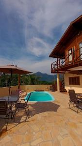 a patio with a pool and chairs and a house at Casa Mar A Vista in Ilhabela