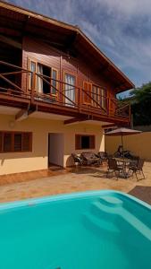 a house with a balcony and a swimming pool at Casa Mar A Vista in Ilhabela