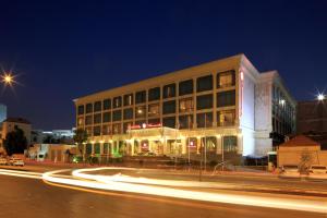 Ramada by Wyndham Hotel Riyadh في الرياض: مبنى في شارع المدينة ليلا