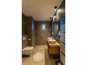 Un baño con dos lavabos y un inodoro. en Modern villa in De Cocksdorp near the beach, en De Cocksdorp