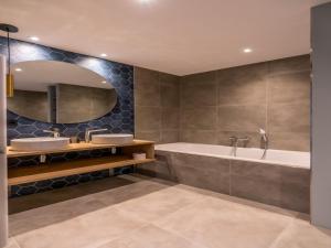 Un baño con dos lavabos, una bañera y un espejo. en Modern villa in De Cocksdorp near the beach, en De Cocksdorp
