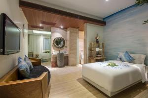 a bedroom with a large white bed and a bathroom at Huangma Holiday Nanhai Museum Hotel in Haikou
