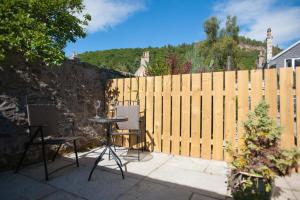 patio con 2 sedie, tavolo e recinzione di Glenernan Self Catering Cottages a Ballater