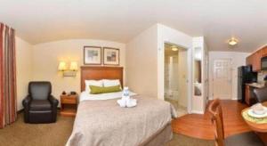 um quarto de hotel com uma cama e uma cadeira em Candlewood Suites Bloomington-Normal By IHG em Normal