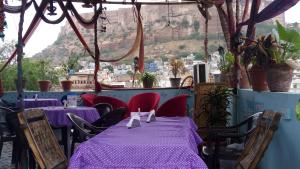 un restaurante con mesas y sillas púrpuras con una montaña en el fondo en Royal Heritage Guest House, en Jodhpur