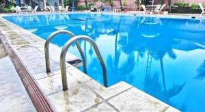 a swimming pool with blue water and white chairs at Sahid Kawanua Hotel in Manado