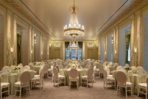 um salão de banquetes com mesas e cadeiras e um lustre em Waldorf Astoria New York em Nova Iorque