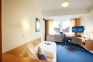 ein Hotelzimmer mit einem Bett, einem Schreibtisch und einem Computer in der Unterkunft IN VIA Hotel in Paderborn