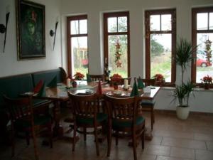 a dining room with a table and chairs and windows at Gasthof Strausberg Nord in Strausberg