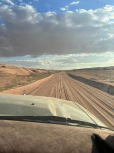 un coche conduciendo en un camino de tierra en el desierto en EXPIORER Desert Camp, en Al Raka