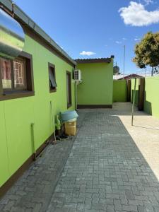 a green house with a brick driveway in front of it at Namasiku's Self Catering in Katima Mulilo
