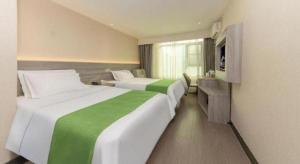a hotel room with two beds and a desk at Vatica Fuzhou West Second Ring Road Xihu Park Hotel in Fuzhou