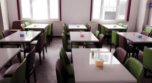 a dining room with tables and chairs and windows at GreenTree Inn Tangshan Xueyuan Road Business Hotel in Fujiatun