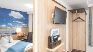 a hotel room with a bed and a flat screen tv at Hotel Blauer Karpfen in Oberschleißheim