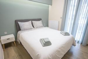 Un dormitorio con una cama blanca con dos toallas encima. en Larissa Luxury Suite, en Larisa