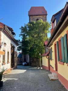 诺伊莱宁恩Zum Burggraf的城镇中一条街道，街道两旁有一棵树和一座塔。 更多22张照片