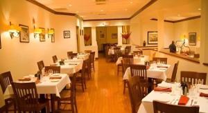 a dining room with white tables and wooden chairs at Garden Plaza Hotel in Passaic Junction