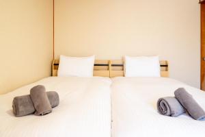 2 letti in una camera con lenzuola e cuscini bianchi di 緑の夢の家 a Furano