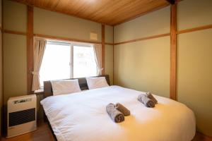 una camera da letto con un grande letto bianco con asciugamani sopra di 緑の夢の家 a Furano
